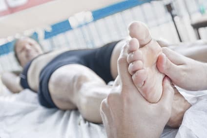 Séance de réflexologie plantaire sur un sportif allongé